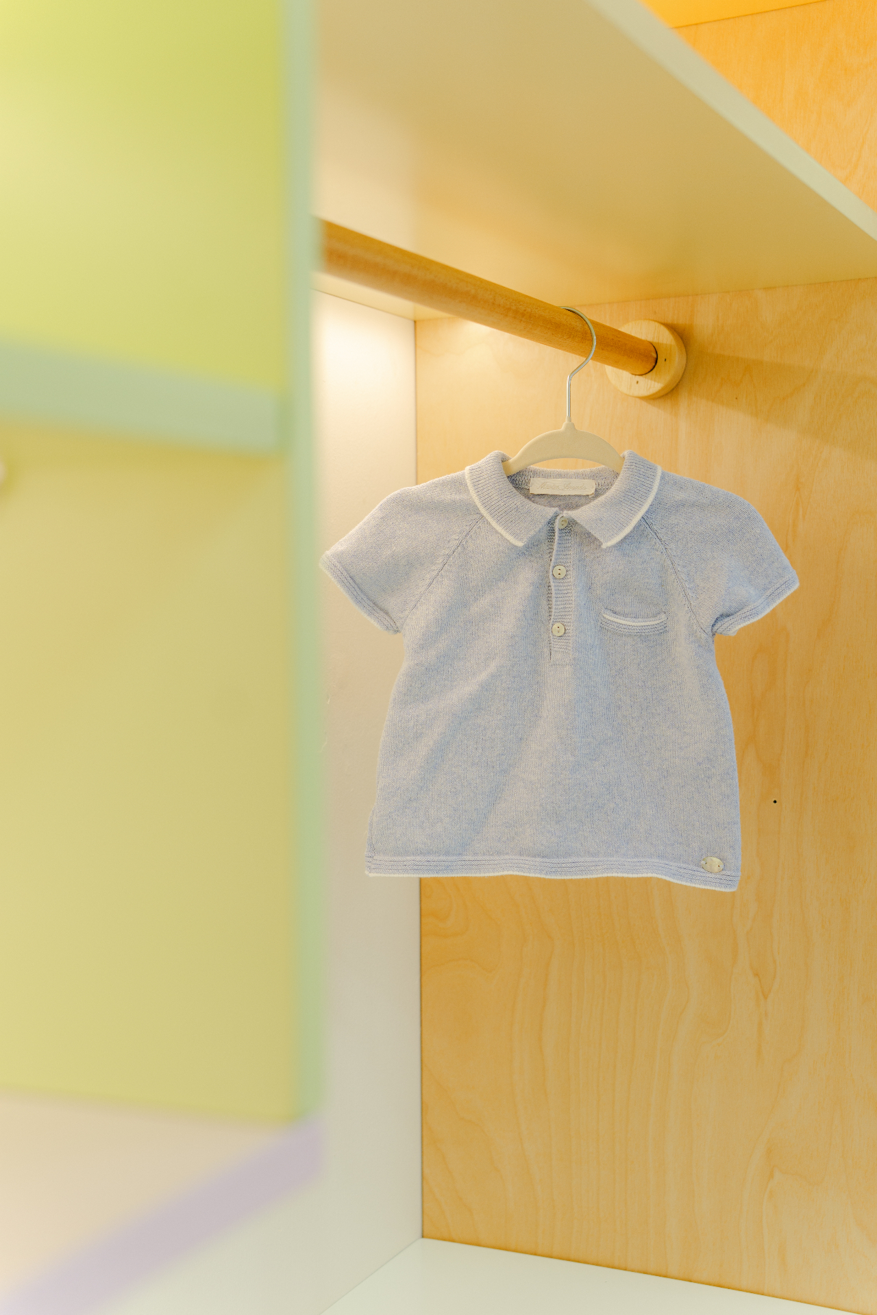 Habitación infantil diseñada por Amanda Simó Studio — perchero de madera con prenda y acentos suaves
