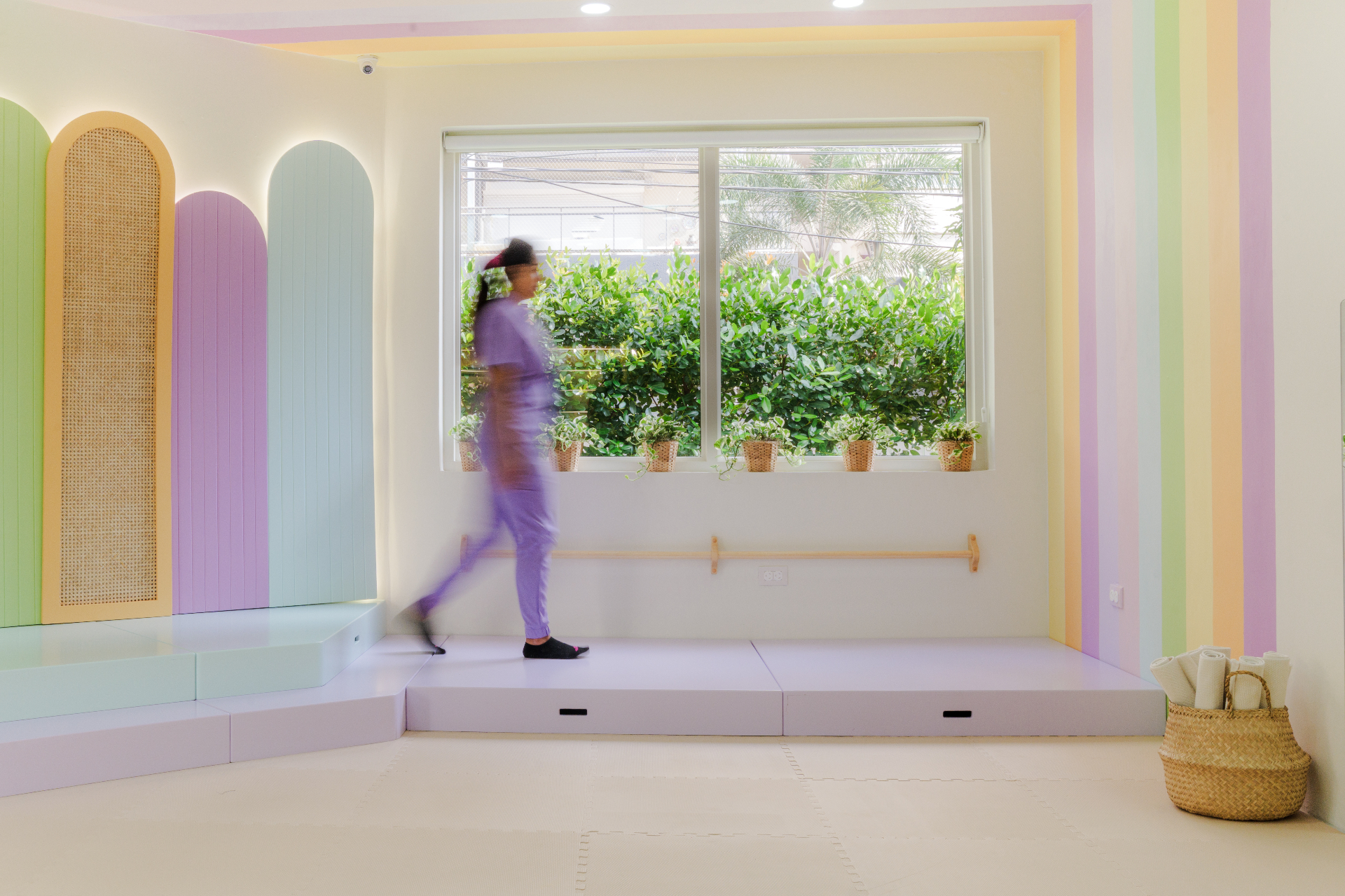 Aula infantil diseñada por Amanda Simó Studio — tonos pastel con ventana central y recorridos suaves