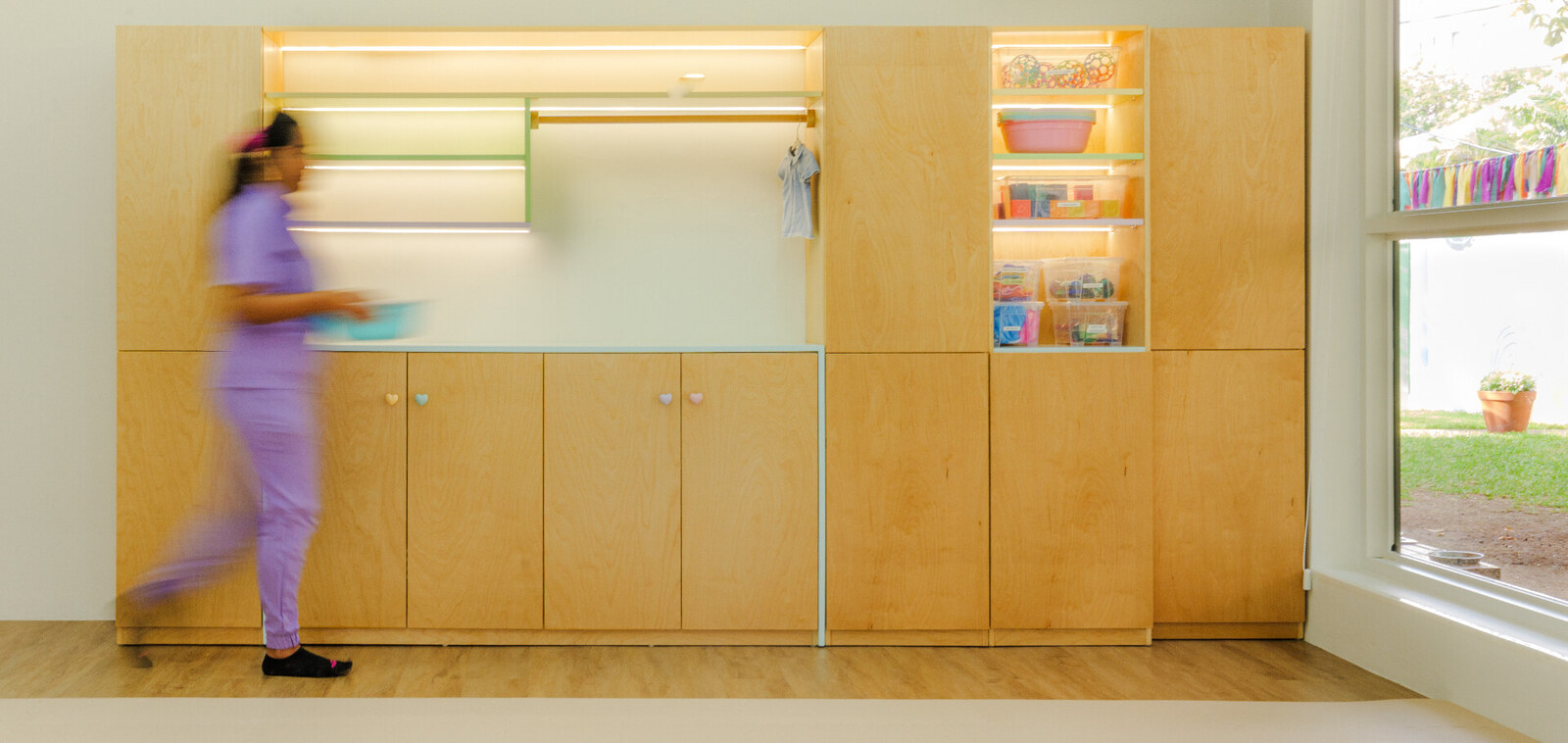 Habitación infantil diseñada por Amanda Simó Studio — armario de madera integrado con iluminación cálida y detalles pastel